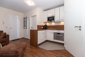 a kitchen with white cabinets and a sink and a couch at Yachthafenresidenz-Wohnung-8101-845 in Kühlungsborn