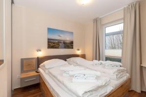 キュールングスボルンにあるYachthafenresidenz-Wohnung-8101-845のベッドルーム1室(大型ベッド1台、白いタオル付)