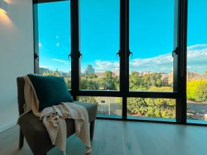 a living room with a chair and large windows at New Magnificent 2BR APT in St Kilda 5A in Melbourne