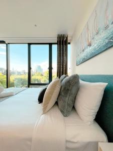 a bedroom with a large white bed with pillows at New Magnificent 2BR APT in St Kilda 5A in Melbourne