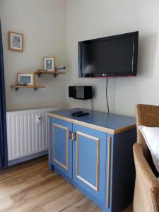 キュールングスボルンにあるYachthafenresidenz-Wohnung-8205-853の青いキャビネット(壁にテレビ付)が備わる客室です。