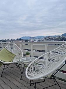 2 weiße Stühle und ein Tisch auf dem Balkon in der Unterkunft Apartments with parking and terrace in Ålesund