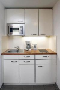 キュールングスボルンにあるYachthafenresidenz-Wohnung-8301-856の白いキャビネット、シンク、電子レンジ付きのキッチンが備わります。