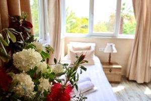 1 dormitorio con 1 cama con flores blancas y rojas en Kemerbag 29 Guest House 12 Yaş Üstü, en Bozcaada