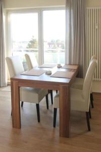einen Esstisch mit weißen Stühlen und ein Fenster in der Unterkunft Yachthafenresidenz - Wohnung 8312 / 864 in Kühlungsborn