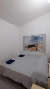 Dormitorio blanco con cama blanca y ventana en Casa Mael, en Villasimius