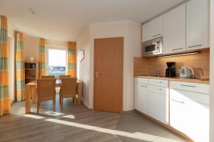 a kitchen with white cabinets and a table with chairs at Yachthafenresidenz-Wohnung-8210-876 in Kühlungsborn
