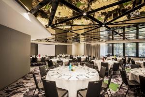 - une salle de banquet avec des tables et des chaises blanches dans l'établissement Capri by Fraser Brisbane, à Brisbane