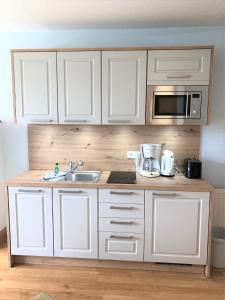 a kitchen with white cabinets and a sink and a microwave at Yachthafenresidenz-Wohnung-9106-881 in Kühlungsborn