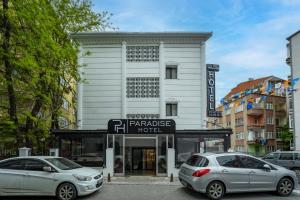 dos autos estacionados frente a un edificio blanco en İstanbul Paradise Hotel, en Estambul