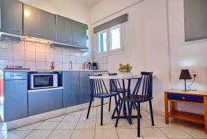 a kitchen with blue cabinets and a table and chairs at Logas Beach Studios Peroulades Corfu in Peroulades +37 photos