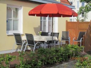 キュールングスボルンにあるStrandstrasse-43-Wohnung-4-9553のパティオ(赤い傘付きのテーブルと椅子付)