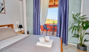 a bedroom with a bed and a balcony with a table at Logas Beach Studios Peroulades Corfu in Peroulades