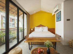 a bedroom with a bed with a yellow wall at TA Danang Boutique Hotel in Da Nang