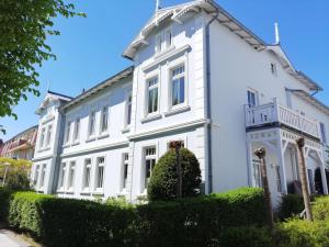 ein weißes Haus mit Büschen davor in der Unterkunft Strandstraße 16 - Wohnung 33 / 9877 in Kühlungsborn