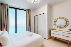a bedroom with a large white bed and a mirror at Address Beach Residence, JBR - Vacationer in Dubai