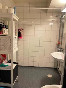 a bathroom with a sink and a white tiled wall at Twayi Luxury Suites in Jönköping