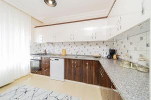 a kitchen with wooden cabinets and white appliances at Spacious and Cozy Apartment in Muratpasa Antalya in Antalya