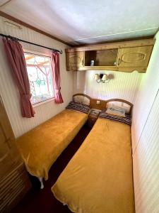 two beds in a small room with a window at Domek Holenderski Podlasie in Sejny