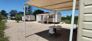 tenda da sole sopra un tavolo e sedie davanti a due case mobili di Agriturismo l' Annunziata a Lizzano