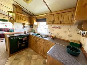 a kitchen with wooden cabinets and a black stove top oven at Domek Holenderski Podlasie in Sejny +14 photos