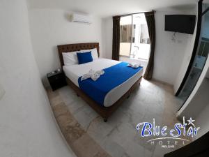 a bedroom with a bed with blue sheets and a window at Blue Star Hotel in Melgar