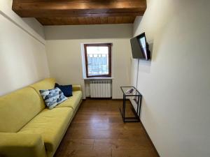 a living room with a yellow couch and a television at Appartamento incantevole sull'antica via Lauretana in Loreto