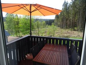 einem Holztisch mit einem Sonnenschirm auf dem Deck in der Unterkunft Sammy's FeWo in Hahnenklee-Bockswiese