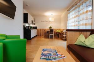 ein Wohnzimmer und eine Küche mit einem Sofa und einem Tisch in der Unterkunft Burgls Apartmenthaus in Tröpolach