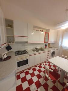 a kitchen with white cabinets and a red and white checkered floor at Holiday Properties Trieste San Francesco in Trieste