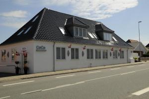 a white building with a black roof on a street at Hotel CoCo Aps in Esbjerg