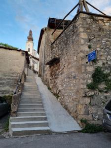 un muro di pietra con una scala che conduce a un edificio con torre di Apartments Deni a Mostar