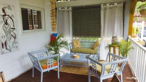 - une terrasse couverte avec 2 chaises, une table et un banc dans l'établissement Les Hauts de Bornave, à Deshaies