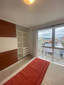 ein Schlafzimmer mit einem großen Fenster und einem Bett mit einem roten Teppich in der Unterkunft Las gardenias in San Salvador de Jujuy