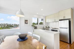 a kitchen and dining room with a table and a refrigerator at Coastal Calm is near to the Beach with BBQ in Auckland