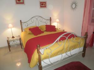 sypialnia z łóżkiem z czerwonymi i żółtymi poduszkami w obiekcie Gite bord de mer jacuzzi w mieście Plougrescant