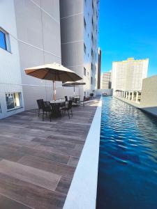 uma piscina com mesas e um guarda-sol num edifício em Aquarius Residence em Fortaleza
