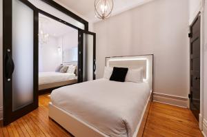 1 dormitorio con 1 cama blanca grande y espejo en Villa Dante By Denstays, en Montreal
