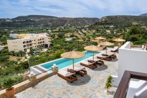 un resort con piscina, sedie e ombrelloni di Aphrodite Luxury Studios & Apartments a Karpathos
