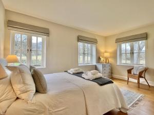 a bedroom with a large white bed with windows at Beaufort Barn by Inspire Stays in Bignor
