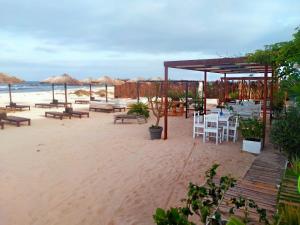 una playa de arena con mesas, sillas y sombrillas en Delfini Resort en Sal Rei