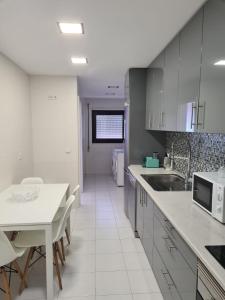 a kitchen with white cabinets and a white table at BRISA MAR in Póvoa de Varzim