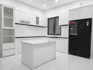 a kitchen with white cabinets and a black refrigerator at An Home - Phòng đơn ngay bãi sau Vũng Tàu in Vung Tau