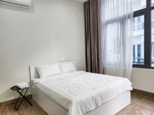 a white bed in a room with a window at An Home - Phòng đơn ngay bãi sau Vũng Tàu in Vung Tau