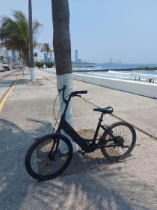 ein Fahrrad, das neben einer Palme auf einem Gehweg parkt in der Unterkunft HOTEL INTI in Boca del Río