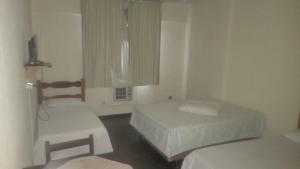 a small bedroom with two beds and a window at HOTEL DOCE LAR in Campos dos Goytacazes
