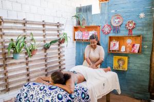 Una donna che fa un massaggio a un uomo in un letto di The Beach Hostel Milagres a São Miguel dos Milagres
