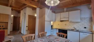 a kitchen with white cabinets and a table with chairs at Casa Soraruf in Campitello di Fassa