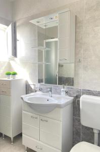 ein Badezimmer mit einem Waschbecken, einem WC und einem Spiegel in der Unterkunft Jolie Ann Marie apartment in Kaštela