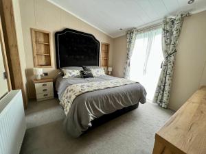 een slaapkamer met een groot bed en een raam bij Wyndham Lodge in South Cerney